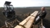 Inmates operate a tractor and a seeder while sowing barley.