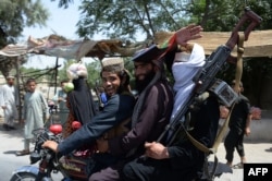 Taliban militants ride a motorbike as they took to the streets to celebrate a cease-fire on the second day of Eid on the outskirts of Jalalabad on June 16.