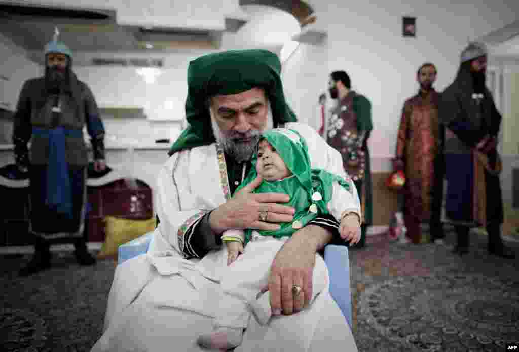 Performer Ali Aghazedeh, representing the Prophet Muhammad's grandson, Imam Hussein, holds a child during a Ta'zieh scene.