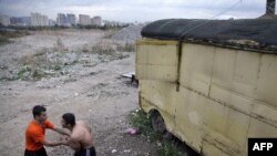 Two Tajik migrant workers relax after a day's work with the Moscow skyline behind them. (file photo)