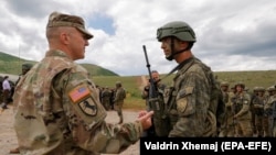 Një ushtar amerikan (majtas) bisedon me një ushtar të Forcës së Sigurisë së Kosovës (FSK), pas stërvitjes ushtarake “Defender Europe 21” në fshatin Devë, Kosovë, më 28 maj 2021.