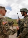 Një ushtar amerikan (majtas) bisedon me një ushtar të Forcës së Sigurisë së Kosovës (FSK), pas stërvitjes ushtarake “Defender Europe 21” në fshatin Devë, Kosovë, më 28 maj 2021.