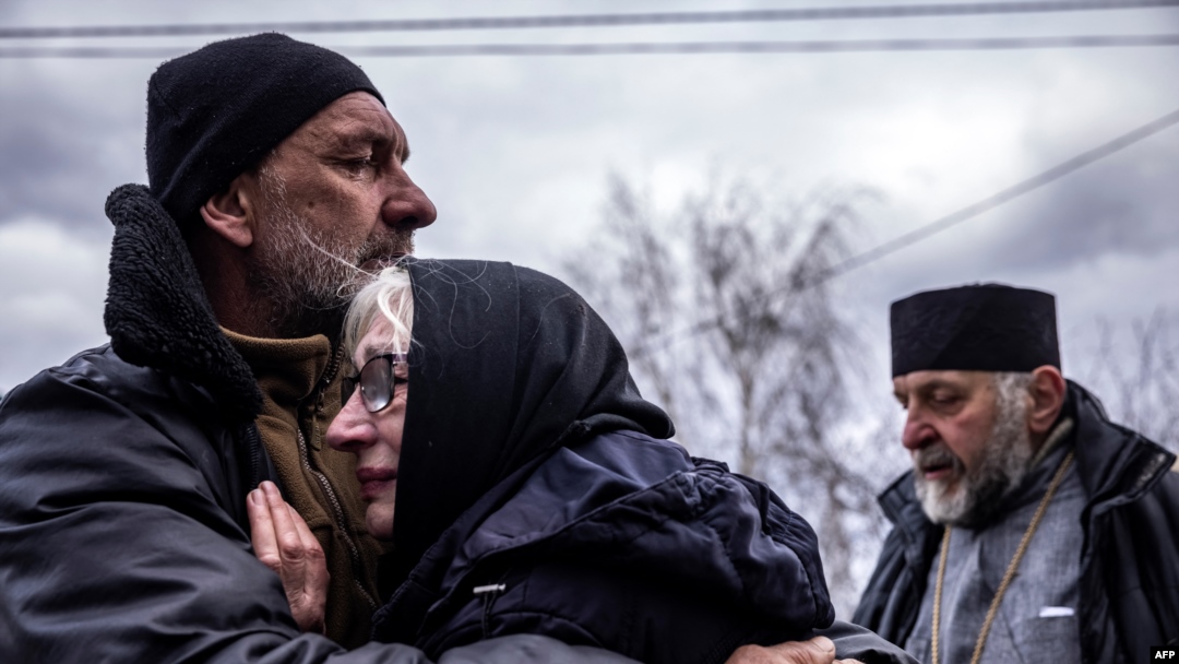 Familia unui civil care a fost exhumat de criminaliști din grădina sa din satul Gostomel, lângă Kiev. 12 aprilie 2022. Anchetatori ucraineni și internaționali documentează uciderea civililor pentru a demonstra posibile crime de război comise de armata Rusiei.
