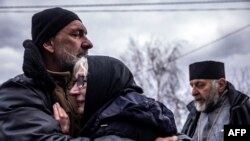 Familia unui civil care a fost exhumat de criminaliști din grădina sa din satul Gostomel, lângă Kiev. 12 aprilie 2022. Anchetatori ucraineni și internaționali documentează uciderea civililor pentru a demonstra posibile crime de război comise de armata Rusiei.
