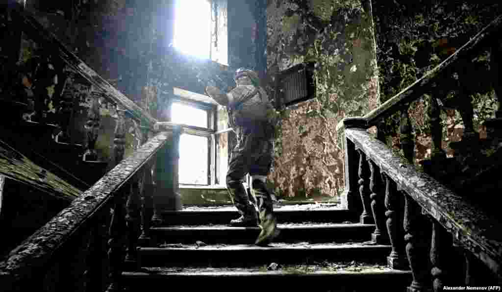Российский солдат поднимается по лестнице в разрушенном драматическом театре Мариуполя, 12 апреля. Фото сделано во время пресс-тура, организованного российскими военными