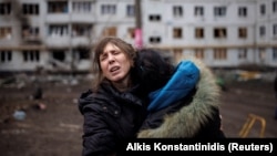 Две женщины плачут во дворе обстрелянного российской армией жилого дома в Харькове, 13 апреля 2022 года