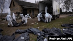 Волонтеры грузят тела убитых в Буче мирных жителей на грузовик для отправки в морг для проведения следственных действий на окраине Киева. 12 апреля 2022 года