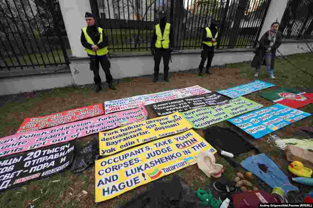 Польская полиция стоит перед посольством России среди плакатов, написанных протестующими на разных языках. Надписи выражают несогласие с вторжением Москвы в Украину