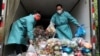 Radnici u zaštitnim odjelima sortiraju vreće sa povrćem i namirnicama u kamionu kojim se raznosi hrana stanovnicima u zatvorenim dijelovima grada Šangaja, 5. april 2022. 