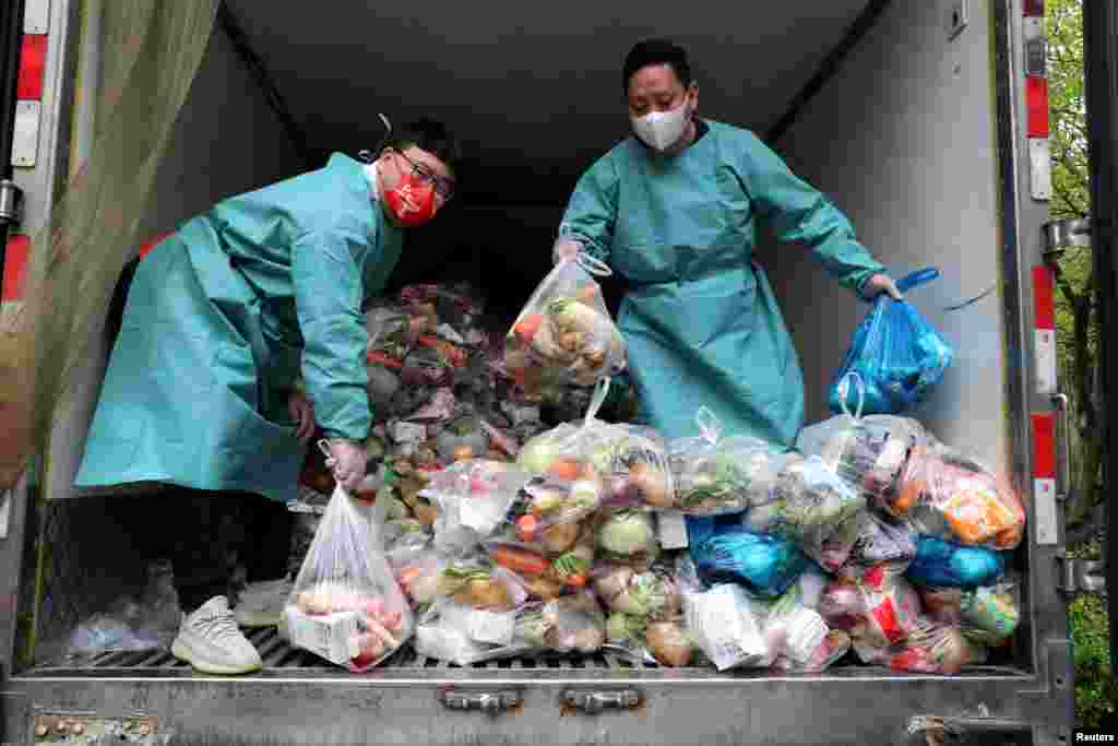 Radnici u zaštitnim odjelima sortiraju vreće sa povrćem i namirnicama u kamionu kojim se raznosi hrana stanovnicima u zatvorenim dijelovima grada Šangaja, 5. april 2022. &nbsp;