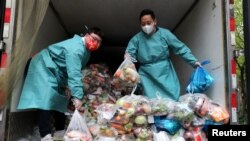 Radnici u zaštitnim odjelima sortiraju vreće sa povrćem i namirnicama u kamionu kojim se raznosi hrana stanovnicima u zatvorenim dijelovima grada Šangaja, 5. april 2022. 