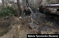 A military sapper picks up unexploded parts of a cluster bomb left after Russia's invasion near the village of Motyzhyn in the Kyiv region on April 10.
