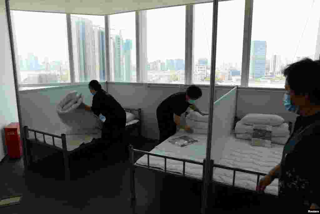 Radnici namještaju krevete u poslovnoj zgradi od 17 spratova kako bi kancelarije prenamijenili u improvizovanu bolnicu za COVID pacijente u Šangaju, 12. april 2022. &nbsp;