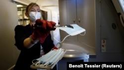 مهماندار ایرفرانس به مسافران ماسک می‌دهد