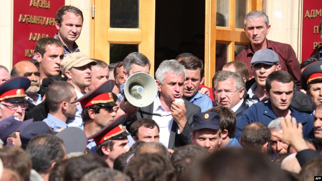 Один из лидеров абхазской оппозиции Рауль Хаджимба (c мегафоном) на митинге перед зданием администрации президента в Сухуме, 27 мая 2014 г.