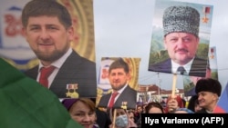 Люди держат фотографии первого президента Чечни Ахмада Кадырова и главы Чеченской республики Рамзана Кадырова во время митинга в центре Грозного, 22 января 2016 г.