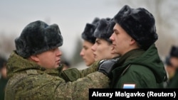 A Russian soldier adjusts the uniform of a conscript at a gathering point before departure for garrisons in Omsk, Russia.