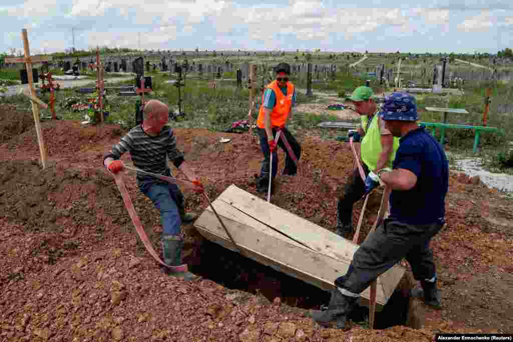 Gravediggers lower a simple wooden coffin into the ground in the Starokrymske cemetery in May. After the siege ended, satellite images showed the Mariupol cemetery rapidly expanding even months later, supposedly as bodies were recovered from the ruins of buildings in the Ukrainian port city. &nbsp;