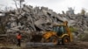 An excavator operates on the ruins of a building destroyed in the course of the Russian invasion in Mariupol, in Russian-controlled Ukraine.