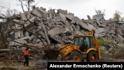 Egy kotrógép dolgozik az orosz invázió során lerombolt épület romjain az orosz ellenőrzés alá került Mariupolban