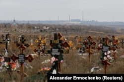 Могили на кладовищі, в тимчасово окупованому селищі Старий Крим поблизу Маріуполя. На фоні видніється металургійний завод імені Ілліча. Україна, 9 листопада 2022 року.