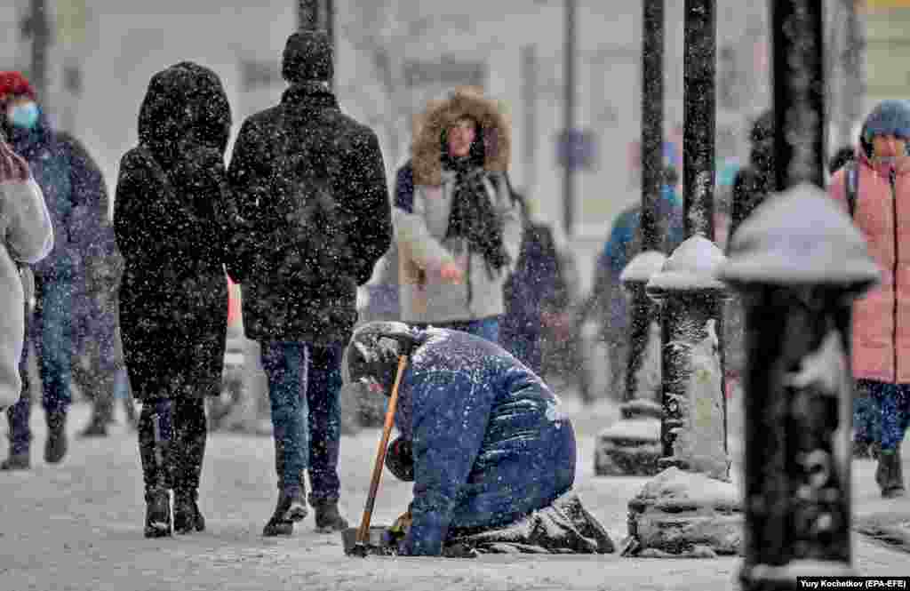 An elderly woman begs on a street during snowfall in Moscow. (epa-EFE/Yury Kochetkov)