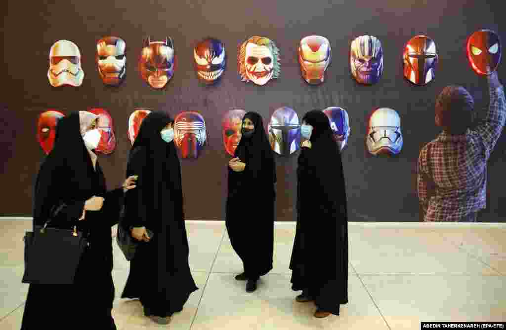 Women stand next to illustrations of comic superheroes and villains, symbolizing Western decadence, during an exhibition at the Mosalah mosque in Tehran.