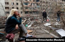 Helyi lakosok egy szétlőtt lakóház udvarán Mariupolban 2022. április 18-án.