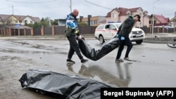 Communal workers carry body bags in the town of Bucha on April 3.