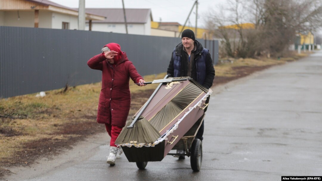 Doi oameni din Borodyanka cară un sicriu pentru a-și înmormânta o rudă, 3 martie 2022. Orășelul din apropiere de Kiev a fost puternic bombardat de armata Rusiei.