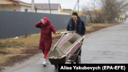 Doi oameni din Borodyanka cară un sicriu pentru a-și înmormânta o rudă, 3 martie 2022. Orășelul din apropiere de Kiev a fost puternic bombardat de armata Rusiei.