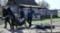 A Ukrainian policeman and municipal workers carry a body bag as they exhume two bodies from graves dug in the yard of a house in the village of Vabliya, near Kyiv, on April 14.