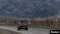 Цивільне авто на тлі пожежі на нафтопереробному заводі в Лисичанську, яка почалась через обстріл. 16 квітня