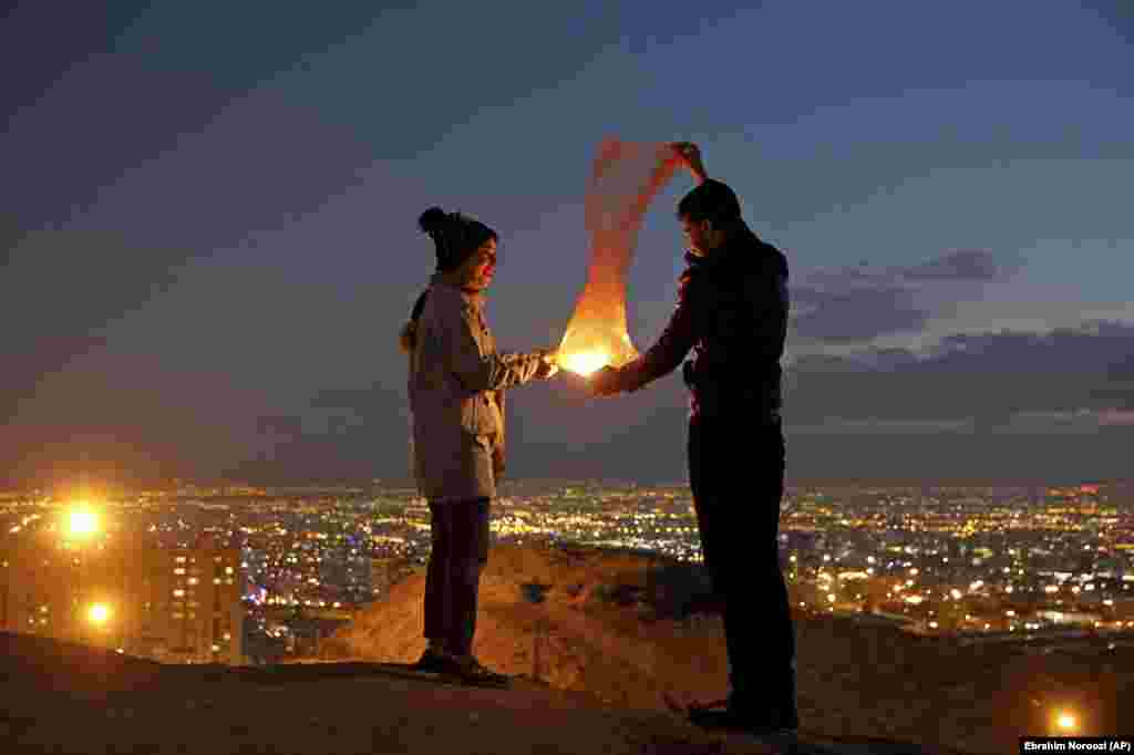 A couple lights a lantern during a celebration, known as &quot;Chaharshanbe Souri,&quot; or Wednesday Feast, marking the eve of the last Wednesday of the solar Persian year, Tuesday, March 19, 2019, in Tehran, Iran.