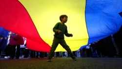 A boy plays underneath a giant national flag during an electoral rally supporting presidential candidate Nicusor Dan in Bucharest on May 11.