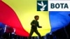 Një fëmijë luan poshtë një flamuri gjigant të Rumanisë, gjatë një eventi elektoral në mbështetje të kandidatit për president, Nicusor Dan, në Bukuresht më 11 maj.
