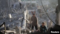 ساکنان محلی در حال بررسی آوار به‌جامانده از حمله روز شنبه اسرائیل به مدرسه‌ای در غزه که محل اسکان آوارگان بود.