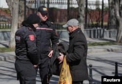Polițiști din Republica Moldova verifică bunurile unui bărbat în timpul unui protest antiguvernamental organizat de mișcările politice de opoziție, inclusiv de partidul „Șor” favorabil Rusiei, Chișinău, 12 martie 2023.