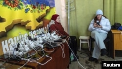 Women charge their devices on January 10 inside a so-called Point of Invincibility center, a government-run shelter that offers basic services and heat during blackouts amid Russia's invasion of Ukraine.