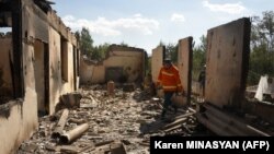Pompierii printre ruinele unei case lovită de un bombardament azer în timpul recentelor confruntări la granița cu Azerbaidjanul, în așezarea Sotk, Armenia, 14 septembrie 2022