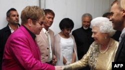 Кралица Елизабет II се среща зад кулисите с Елтън Джон, докато Роби Уилямс (вдясно) ги гледа по време на Диамантения юбилеен концерт пред Бъкингамския дворец в Лондон на 4 юни 2011 г.