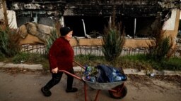 A woman pushes a wheelbarrow past a building in which she used to live that was destroyed by a Russian missile strike in the town of Svyatohirsk in Ukraine's Donetsk region on October 9. 