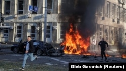 Men run the site of a blast in Kyiv on October 10.