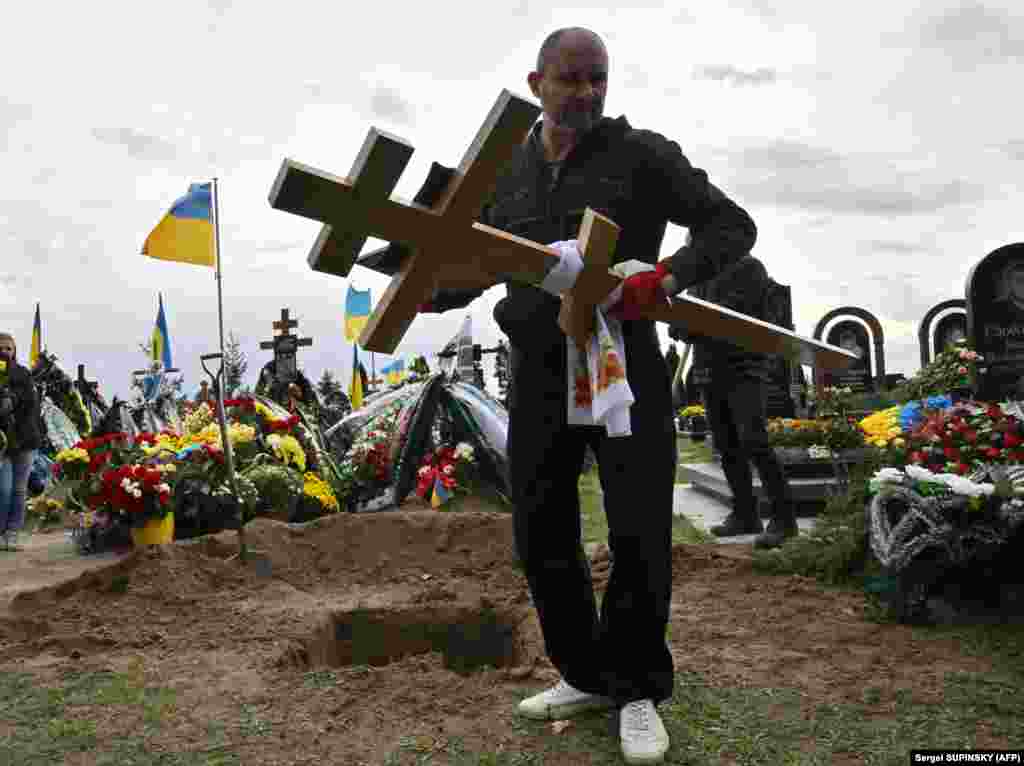 A communal worker carries a cross during the funeral of Mykhaylo Matyushenko, a colonel in the Ukrainian armed forces who was shot down in the sky over the Black Sea in June, at a cemetery in Bucha in the Kyiv region.&nbsp;