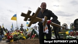 A worker carries a cross at the funeral of Mykhaylo Matyushenko, a colonel of Armed Forces of Ukraine who was shot down in the sky over the Black Sea on June 26, at a cemetery of Bucha, Ukraine, on October 3.