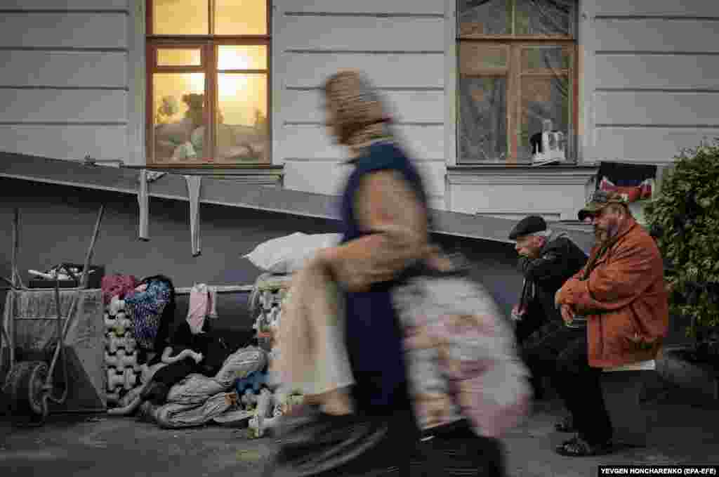 People stand next to a building near the Svyatohirsk Cave Monastery.&nbsp;According to Ukrainian authorities, the major Orthodox Christian monastery was damaged during Russian shelling of the town in June 2022.