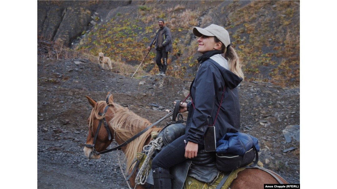 A shepherd and his dog pause to watch Ididze lead her horses toward the Abano Pass.