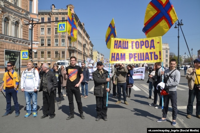 People march carrying the flag of Ingria in St. Petersburg on May 1, 2019.