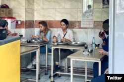 Două tinere iau micul dejun într-un restaurant din Teheran, fără hijab.