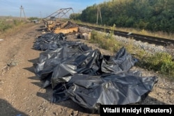 Bags containing bodies lie next to cars from a civilian convoy, which Ukrainian authorities say was hit by shelling from Russian troops near the village of Kurylivka in the Kharkiv region.